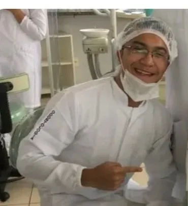 Daniel sorrindo de jaleco na clínica da faculdade